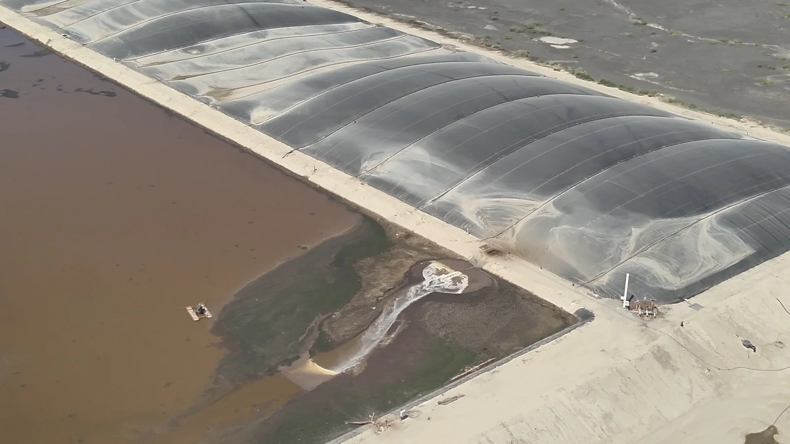 Aerial view of Philip Verwey Dairy's covered digester lagoon beside an open lagoon of brown manure water