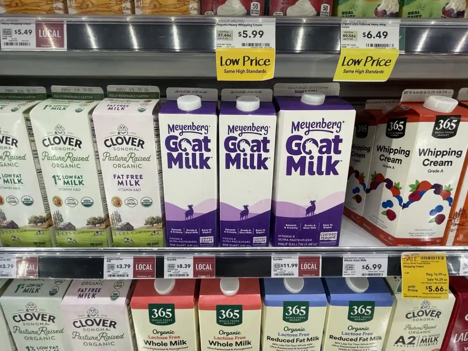 Meyenberg Certified Humane goat milk cartons displayed on Whole Foods Market shelves in California alongside Clover Sonoma Pasture Raised Organic milk — both sourced from factory farms documented by animal rights investigators